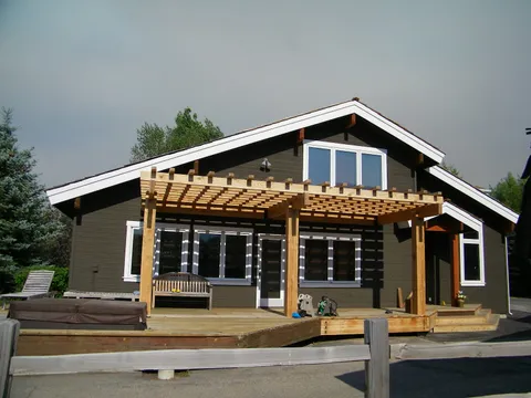 Craftsman-style home exterior with a cedar pergola shading a back deck and hot tub