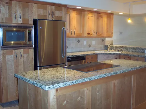 Kitchen island with granite countertop, knotty alder cabinets, and stainless appliances