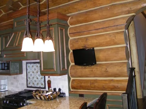 Log cabin interior with exposed log beams and a wall-mounted TV
