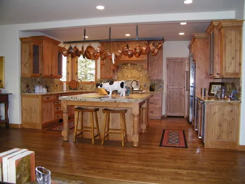 Knotty pine kitchen island with a hanging copper pot rack and hardwood floors