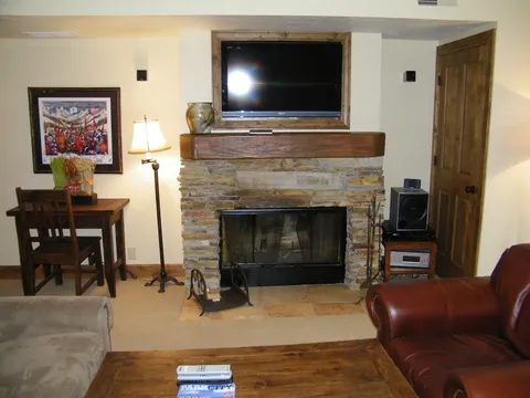 Living-room fireplace with a stacked-stone surround beside a leather armchair
