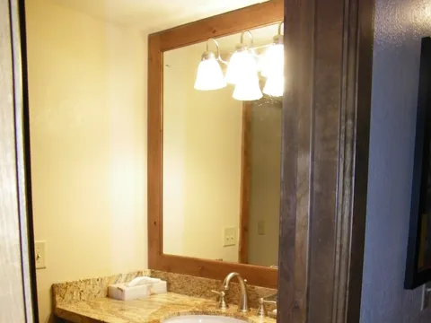 Bathroom vanity with a granite countertop and wood-framed mirror