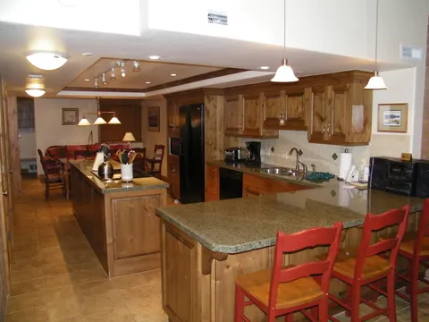 Long kitchen island topped with granite and lined with red bar stools