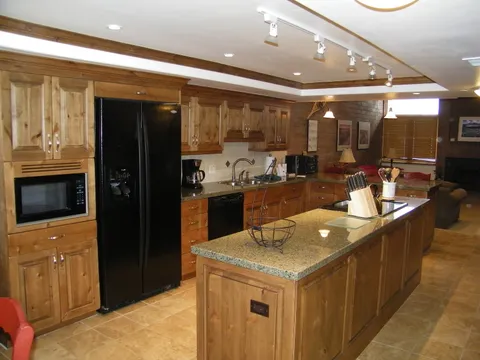Rustic pine cabinets paired with black appliances and a granite island