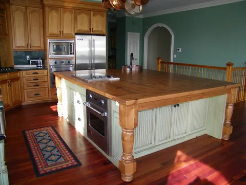 Wood-plank island beside a built-in stainless oven and refrigerator
