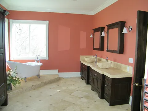 Clawfoot tub and dual vessel sinks in a coral-walled bathroom