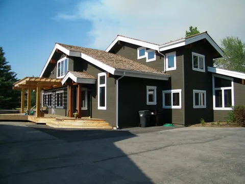 Two-story home exterior with dark siding, white trim, and a cedar-shake roof