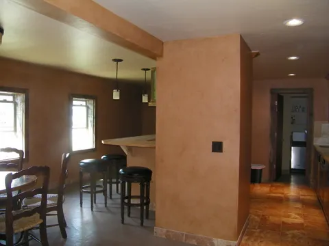 Bar stools and a dining table in an earthy plaster-walled room