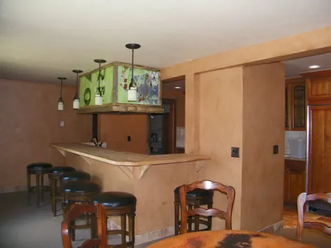 Salvaged green sign mounted above a bar with leather-topped stools