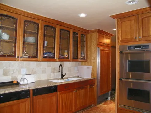 Double stainless wall ovens set into glass-front cabinetry