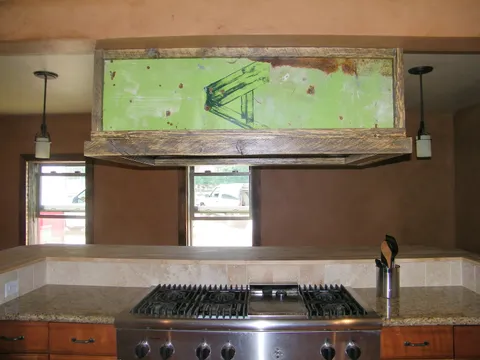 Gas cooktop beneath a weathered reclaimed-wood vent hood