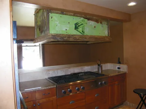 Professional-style range flanked by cherry cabinets under a rustic hood