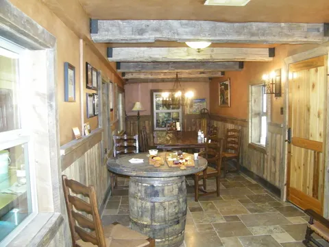 Whiskey-barrel table topped with a cheese board under exposed beams
