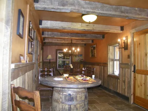 Reclaimed-wood beams framing a dining room with a barrel-top table