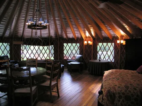 Open living and dining area inside a yurt with a round table and chandelier
