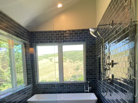 Freestanding tub and tiled bench in a dark-tiled bathroom