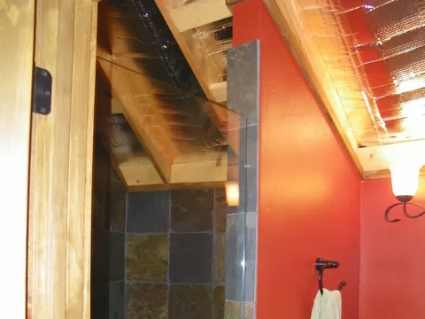 Slate-tiled walk-in shower set against a deep-red bathroom wall