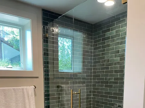 Glass shower with dark green tile and built-in bench