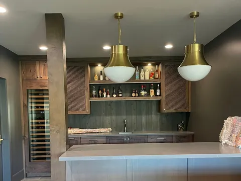 Wet bar with gray cabinets, wine storage, and pendant lights