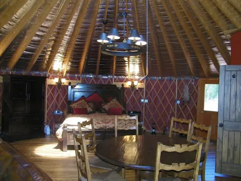 Dark-wood bed dressed with red pillows in a yurt sleeping area