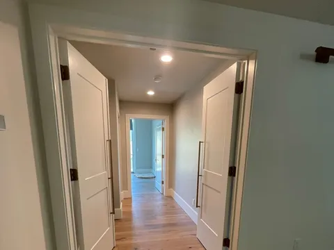 Wood-floored hallway with white walls and several doorways