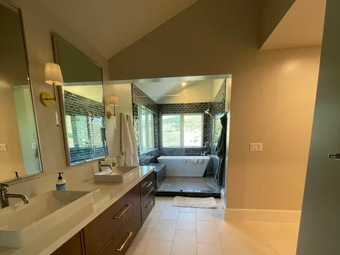 Long wood vanity beneath a wide mirror in a light-tiled bathroom