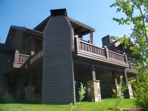 Elevated wood deck with stone pillars on a mountain home exterior