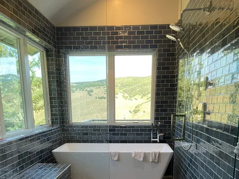 Freestanding tub centered in a dark-tiled bathroom