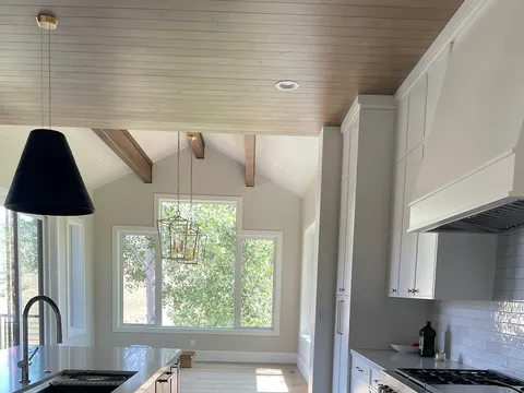 Narrow kitchen with white cabinets, dark counters, and a window