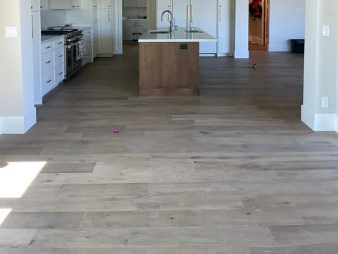 Open kitchen with a white island, wood cabinetry, and brass pendant light