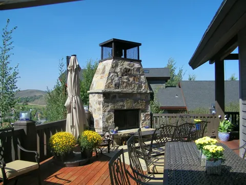 Patio seating beside a stone fireplace overlooking mountain scenery