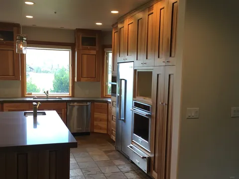 Kitchen island with wood cabinetry above slate-tile flooring