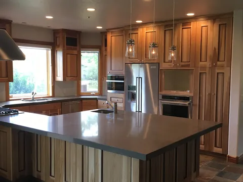 Pendant lights over a wood-cabinet kitchen with stainless appliances