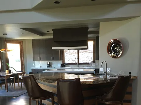Granite island with leather bar stools opening to the dining room