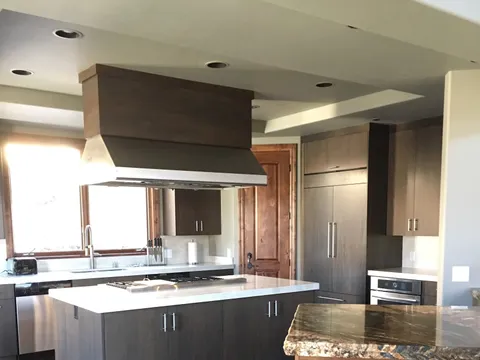 Stainless range hood above a dark-wood island with granite counter