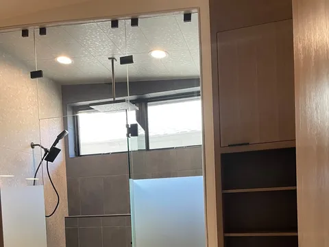 Walk-in shower with glass enclosure, tiled walls, and built-in niches