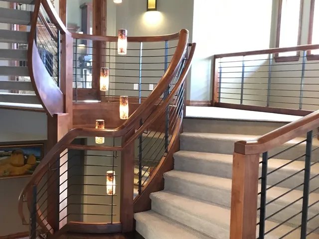Curved staircase with a wood handrail and cable railing