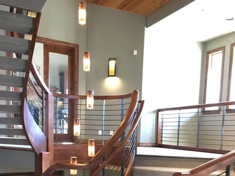 Curved staircase with a wood handrail and cable railing
