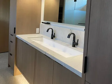 Double-sink bathroom vanity beneath a broad mirror and pendant lights
