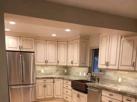 L-shaped kitchen with cream glazed cabinets and a copper farmhouse sink