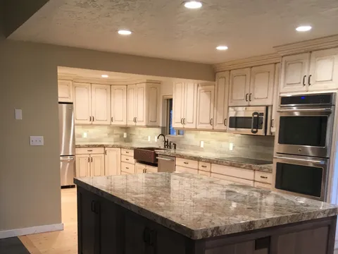 Granite island facing cream cabinetry with double wall ovens