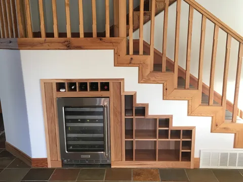 Built-in wine cooler and open shelving tucked beneath a staircase