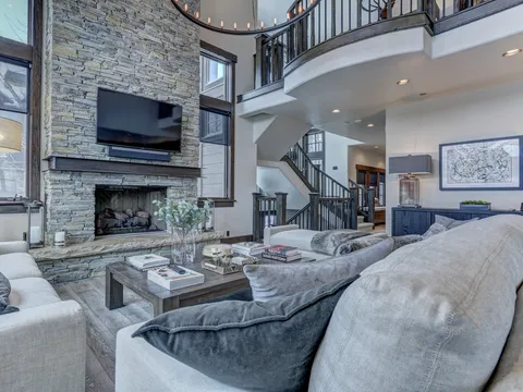 Two-story great room with a stone fireplace and a curved upper balcony