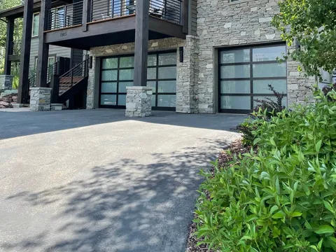 Modern stone house exterior with balcony and landscaped entry