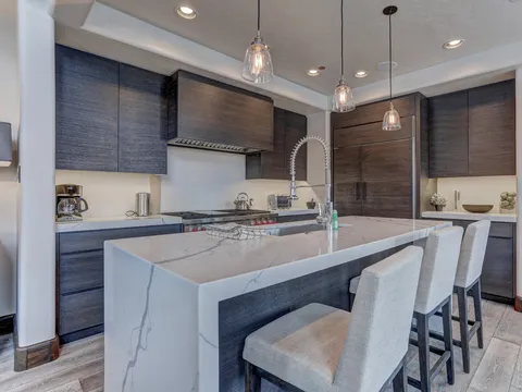 Sleek island with a waterfall quartz countertop and pendant lighting