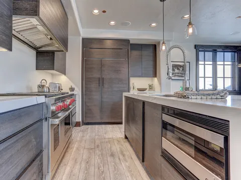 Galley kitchen with dark cabinetry, a gas range, and hardwood flooring