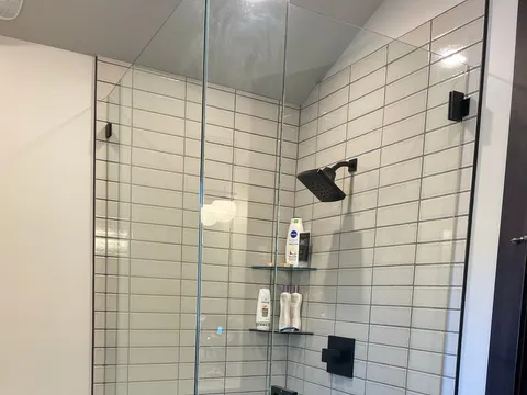 Walk-in shower with white tile, black fixtures, and hexagonal floor tile