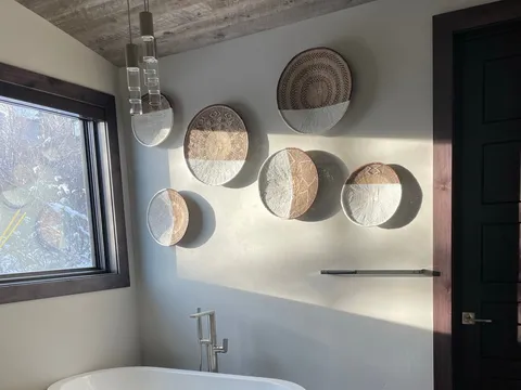 Freestanding tub below round wall decorations and a window