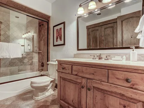 Bathroom pairing a tile shower surround, tub, and wood vanity cabinet