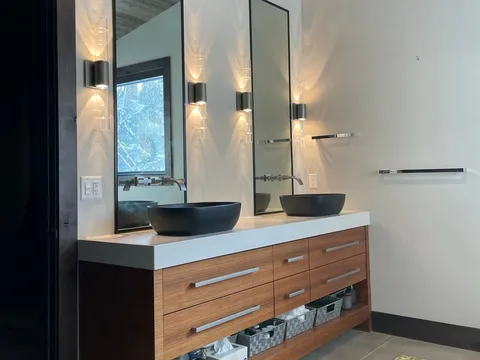 Wood floating vanity with two sinks, broad mirrors, and a patterned floor mat